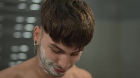 Closeup Young Man Removing Shaving Foam From Lips Standing Indoors in Bathroom