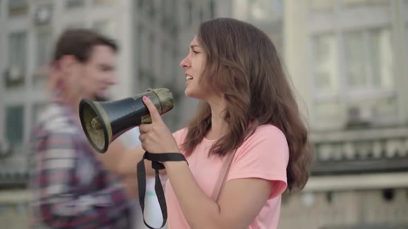 Young Eco-activist Shouting Through Megaphone and People with Banners Joining Leader in