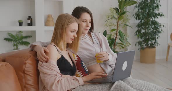 Two lesbians are on the couch Two lesbians are working on a laptop LGBT Lesbian Bisexual Love