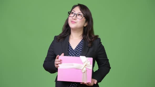 Mature Beautiful Asian Businesswoman Thinking While Holding Gift Box