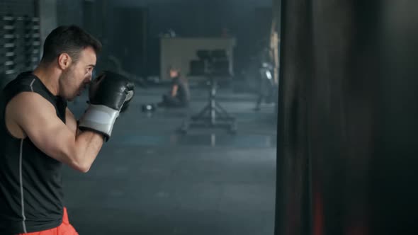 Aggressive Professional Fighter Is Training with a Punching Bag, Inflicting a Furious Blow. The