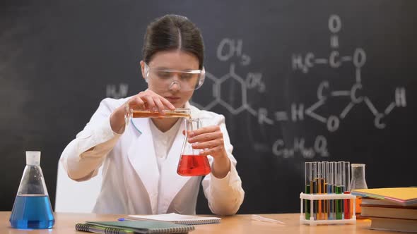 Chemistry Student Mixing Liquids in Laboratory and Writing Results, Experiment