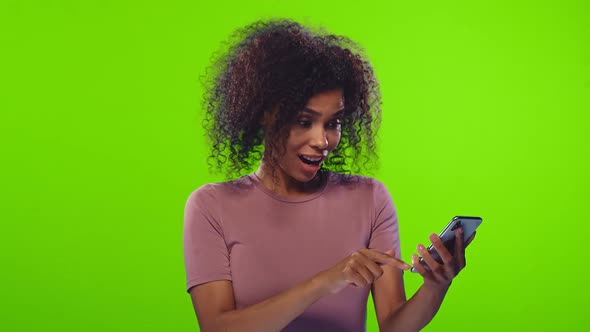 Surprised Dark Skinned Lady Points at Smartphone Device