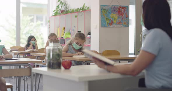 Children in the Classroom at School in Masks Sit in the Classroom and Listening the Teacher