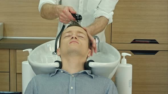 Handsome Man Having His Hair Washed in Hairdressing Saloon. Young Man Lying with His Eyes Closed in