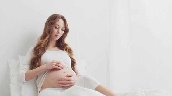 Pregnant woman touching her belly. Pregnancy, motherhood, and expectation concept.