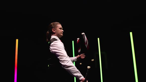 Circle Movement Camera Around Professional Circus Performer Spinning Pins Against a Black Studio