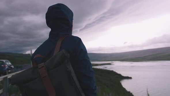 Man with a Backpack Enjoying View of Stromy Clouds Over the Lake Cinematic Shot