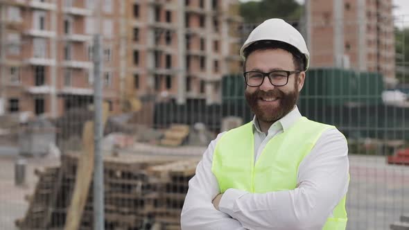 Portrait of Smiling Architect Man Standing on the Construction Site with Crossed Hands Looking at