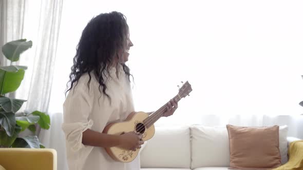 Woman Playing Ukelele Standing in Living Room