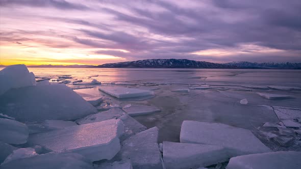 Time lapse during colorful sunset looking past ice slabs on Utah Lake