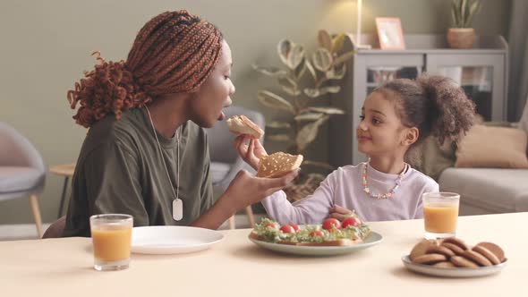 Mother and Daughter Feeding Each Other with Homemade Sandwiches alt