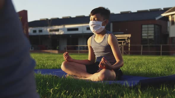 Boy wearing face mask performing yoga in the garden