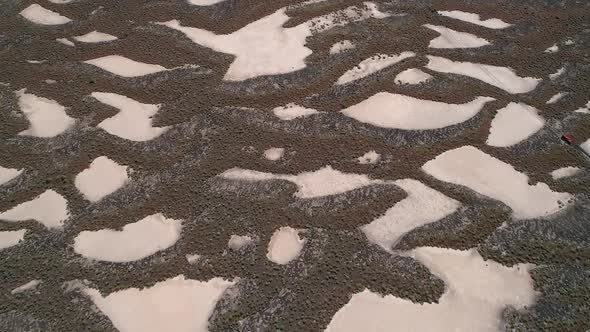 Aerial view looking down at desert terrain with sand trapped in the landscape