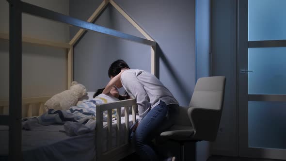 Caring Chinese Mom Putting Little Daughter To Bed