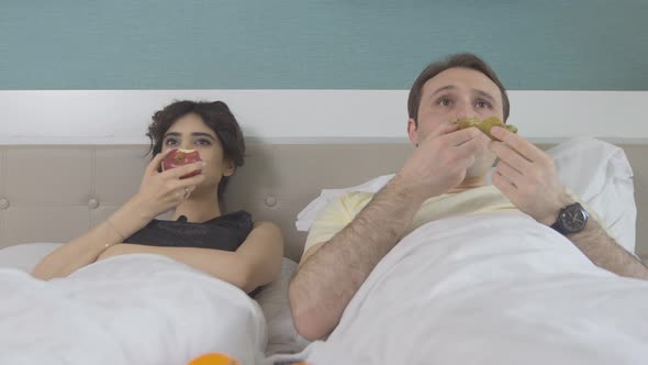 Fruit and TV enjoyment, a couple in the bedroom.