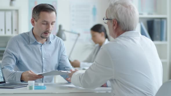 Male Patient Signing Health Service Agreement in Medical Office