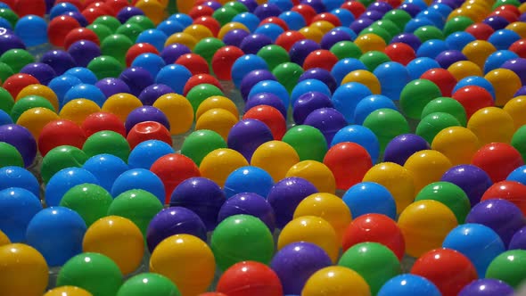 Colorful Small Plastic Balls Floating and Moving in Water, Closeup View.