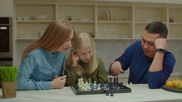 Joyful Hearing Impaired Family and Preadolescent Girl Playing Chess Game at Home