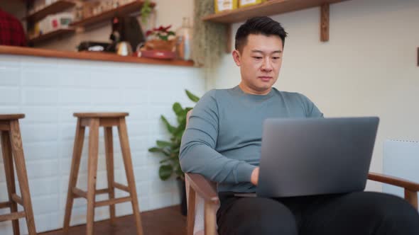 Concentrated Asian young man working by laptop