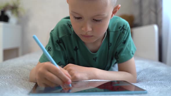 A school-age boy draws with a stylus on a digital tablet