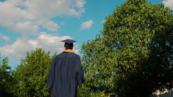 Rear View of the University Graduates Student at Silhouette Sunset Goes on the Road