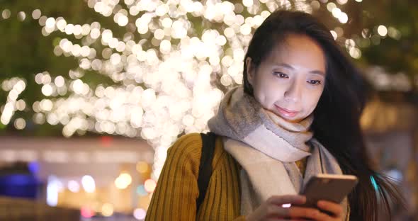 Woman look at mobile phone in city at night