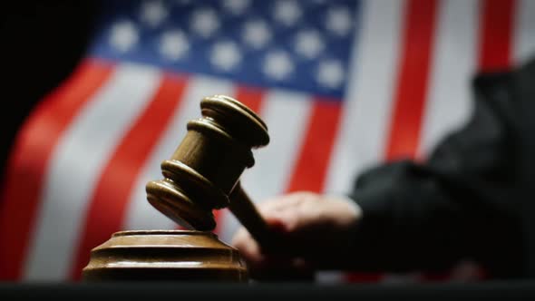 Judge Hammering With Wooden Gavel Against Waving American Flag In USA Court Room