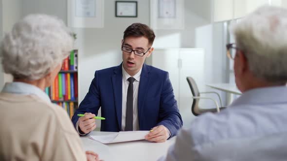 Bank Manager Explain Mortgage Details to Aged Couple in Modern Bank Office