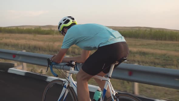 View from the back of a professional male cyclist riding a road bike, leaning his elbows on the stee