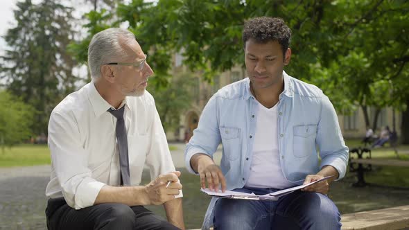 Literature teacher giving advice to Hispanic student about essay writing