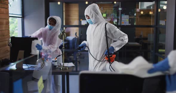 Team of health worker wearing protective clothes cleaning office using disinfectant sprayer