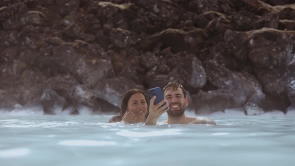 Couple Looking At Phone In Lagoon Geothermal Spa