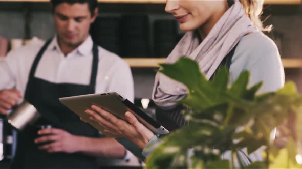 Waitress using digital tablet at counter