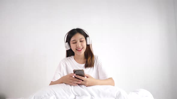 Pretty Woman listening to music with headphones in bedroom.