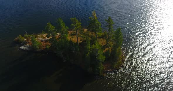 Aerial Circling Around Tiny Island on Peaceful Lake During Peak Fall