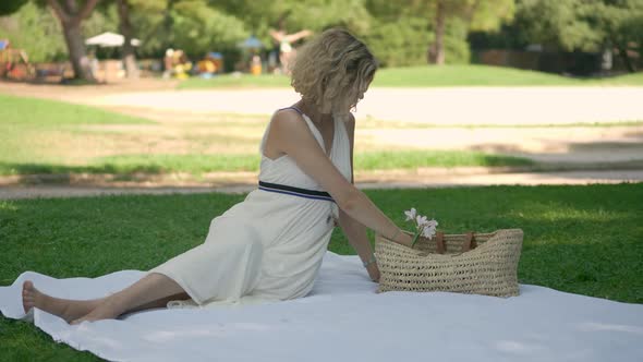 A Woman's Boyfriend Arrives for a Lovely Picnic Date in a Park, Static Wide, Slow Motion