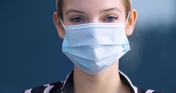 Close-up Portrait of a Female Face in a Protective Medical Surgical Mask, a Young Girl Stands Alone