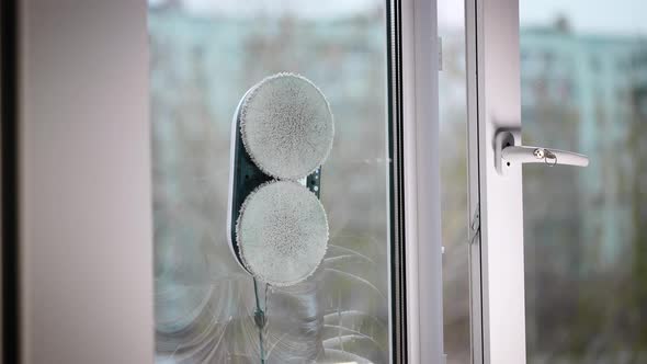 The Automatic Robot Assistant Washes the Glass of the Window