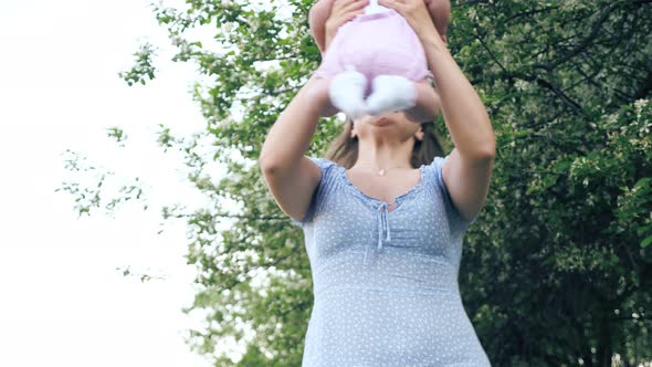 Amazed Mother with Loose Fair Hair Spins with Baby Girl