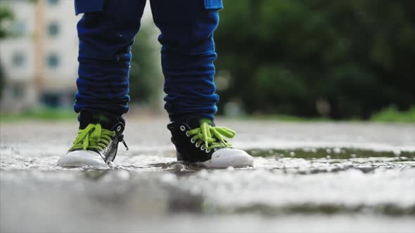 Low Angle, Close-up, Unrecognizable Kids Running Through Puddles Summer Day After Rain. Carefree