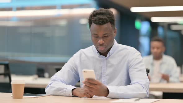 Attractive African Businessman Using Smartphone in Office