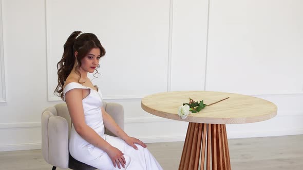 Elegant Bride in White Dress Posing for the Photographer While Sitting