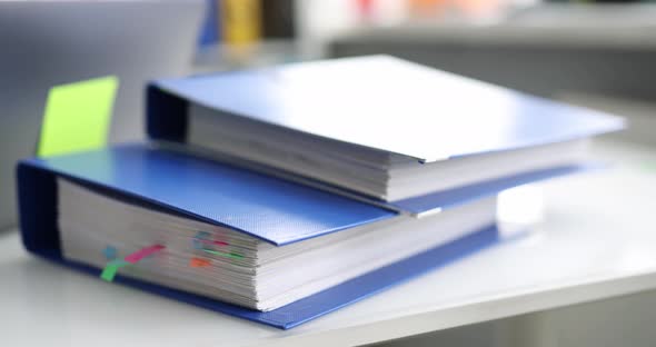 Stack of Reporting Paper Documents in Blue Folder with Bookmarks Desktop