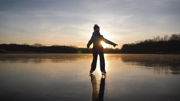 Cute Little Girl Is Going Skate Outdoors at Sunset. A Schoolgirl Enjoying Ice Skating at Frozen Lake