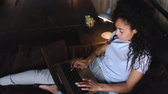 Young Attractive AfricanAmerican Woman Using Laptop Computer in the Bed and Smilling in Camera Slow