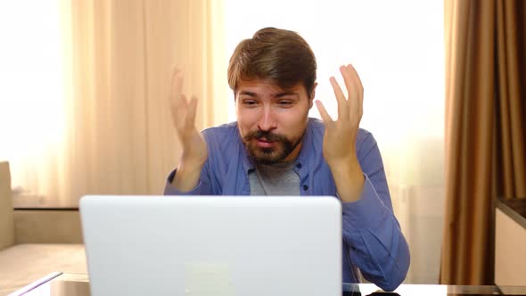 Young Stressed Handsome Man Working in Living Room Shouting at Laptop Screen and Being Angry