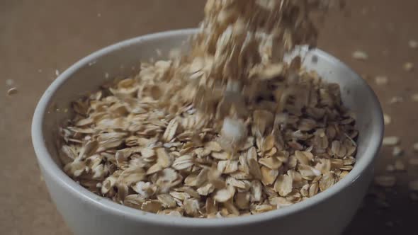 close-up,Slow motion of oatmeal falling into a wooden bowl. Whole grain cereals