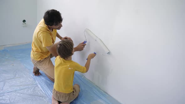 A Father and Son Both Wearing a Yellow Tshirt Paint the Wall Using a Roller Painter