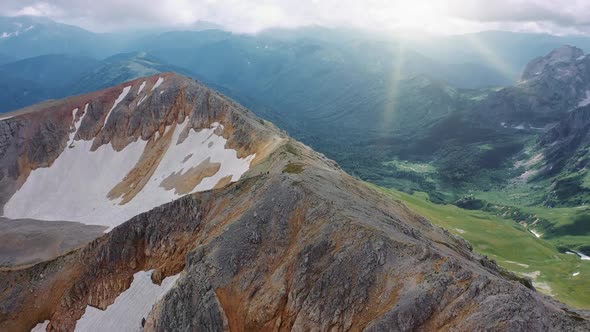 Aerial Shot From Brown-gray Mountain Covered with Snow on Beautiful Valley of Mountains, Covered